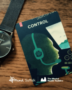 A card with the word 'Control' at the top and an illustration of a person at a cockpit of an aeroplane rests on a wooden table, next to a wristwatch.