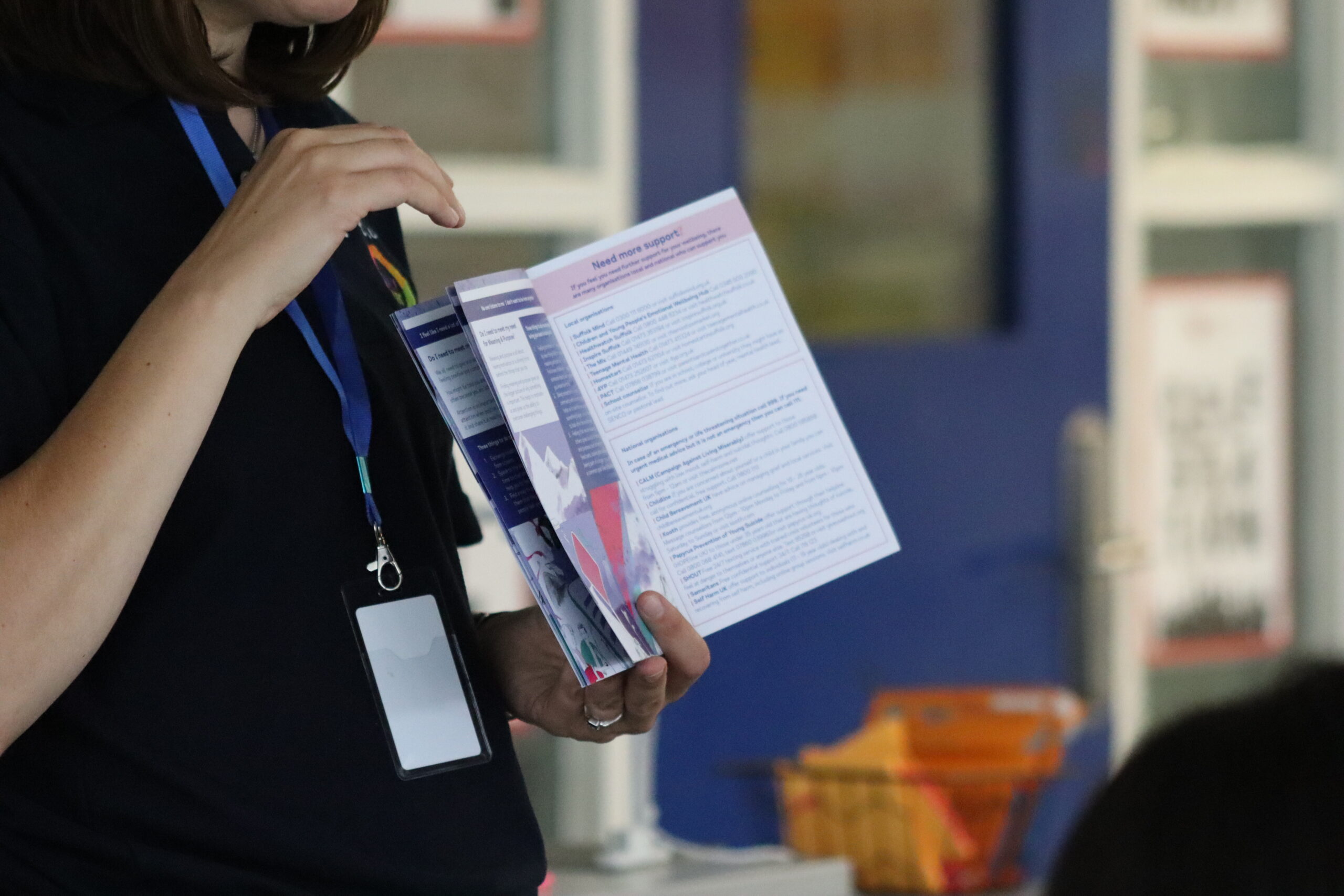 A person in a classroom holds up an open booklet, the header of the page says 'Need support?'