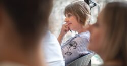 People sitting down in a training setting, listening to a speaker who is out of shot. A woman rests her head on her hands as she pays attention.