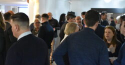 A group of people in a networking setting are standing in clusters, talking to each other